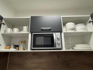 a microwave in a kitchen with plates and dishes at Prime Host Flair Apartment in Karlsruhe