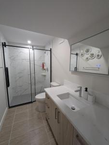 a bathroom with a toilet and a sink and a shower at Mountview Maison in Red Deer +40 photos