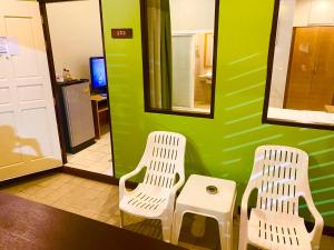 two white chairs in a room with a green wall at Spice & Sea Resort in Kata Beach