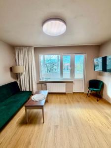 a living room with a green couch and a table at Freshly Renovated Black & Sand Studio in Liepāja