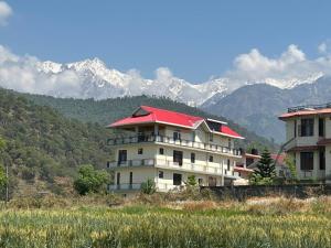 a building with a red roof with mountains in the background at Dhauladhar Vista in Pālampur