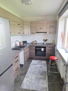 a kitchen with wooden cabinets and a red stool at Spacious & sunny apartment with a balcony in Tartu