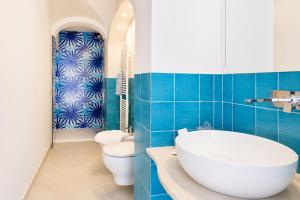 a bathroom with a tub and a toilet and blue tiles at La Terrazza del Sole a Positano in Positano