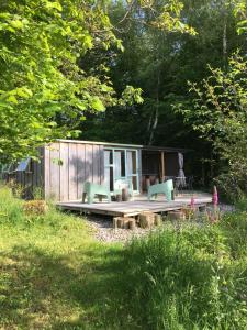 a small cabin with two chairs on a wooden deck at Les Jardins d'Yzorche in Saint-Bazile-de-la-Roche