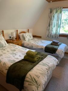 a bedroom with two beds and a window at West Haven Lodge in Aultbea