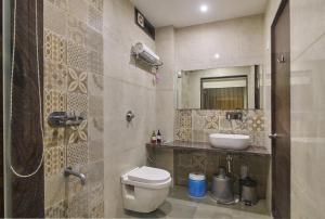 a bathroom with a toilet and a sink and a mirror at Hotel Hrushikesh in Shirdi