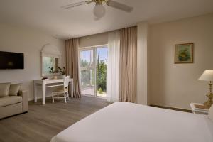 a hotel room with a bed and a desk and a window at Sandy Villas Resort by Rizos Resorts in Línia +50 photos