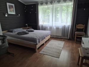 a bedroom with a bed and a large window at KLĀNU MĀJA in Varakļāni