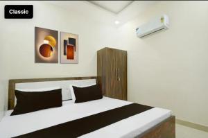 a bedroom with a large white bed with black pillows at Tansen Guest House in Gwalior