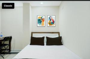 a bedroom with a white bed with three paintings on the wall at Tansen Guest House in Gwalior