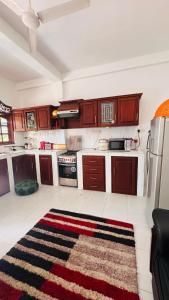 a kitchen with wooden cabinets and a rug on the floor at Chamo Villa by DrMocktail in Beruwala