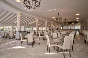 a dining room with white tables and chairs at Sandy Villas Resort by Rizos Resorts in Línia