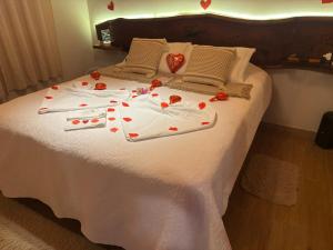 a bed with red roses and hearts on it at Chalé Recanto do Quilombo - MV in Camanducaia