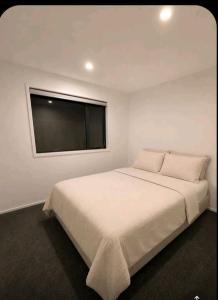 ein weißes Schlafzimmer mit einem großen Bett und einem Flachbildfernseher in der Unterkunft Havencate in Nakuru