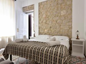 a bedroom with a bed with a stone wall at Sunset Baunei in Baunei +23 photos