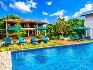 a pool with chairs and umbrellas next to a house at Ceylon Breeze Sigiriya in Sigiriya