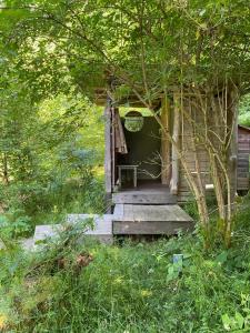 a small cabin with a wooden porch in the woods at Les Jardins d'Yzorche in Saint-Bazile-de-la-Roche +5 photos