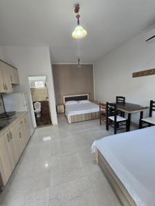 a room with two beds and a table and a kitchen at Summer Tale Rooms in Tale