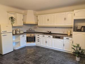 Eine weiße Küche mit weißen Schränken und Geräten in der Unterkunft Kornkammer - Ferienhaus NaheZeit Bostalsee in Nohfelden