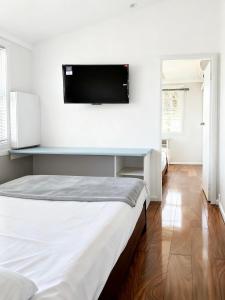 a bedroom with a bed and a flat screen tv on the wall at Coffs Coastal Cabin, Central & Convenient in Coffs Harbour