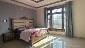 a bedroom with a bed and a large window at Dhauladhar Vista in Pālampur