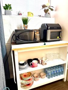 a microwave oven on a shelf with cups and dishes at Room in niagara falls Pluto studio in Niagara Falls