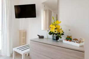 a living room with a tv and flowers on a dresser at Scirocco Guest House in Brindisi