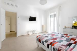 a white bedroom with a bed and a tv on the wall at Scirocco Guest House in Brindisi