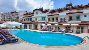 a pool in front of a hotel with chairs and umbrellas at Konfor Suite Otel in Oludeniz