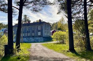 a large blue house with a dirt road in front at Boende i Sandarne in Sandarne