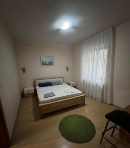 a bedroom with a bed and a green rug at Kosvegas Apartment in Kosovo Polje