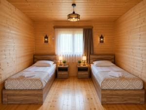 two beds in a room with wooden walls at Ushba Hill Panoramic Lodge Becho in Mestia