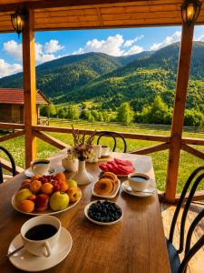 a wooden table with fruit and coffee on it with a view at Ushba Hill Panoramic Lodge Becho in Mestia
