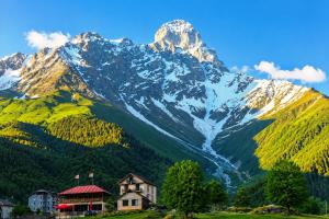 a mountain with a house in front of it at Ushba Hill Panoramic Lodge Becho in Mestia