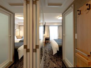 a hotel room with two beds and a door to a bedroom at APA Hotel Kyoto Gion Excellent in Kyoto