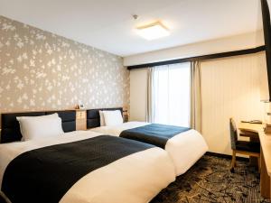 a hotel room with two beds and a desk at APA Hotel Kyoto Gion Excellent in Kyoto