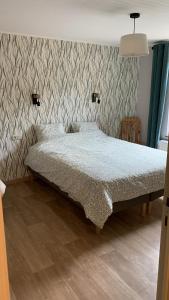 a bed in a bedroom with a patterned wall at Au fil de la Semois in Bohan