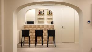 a kitchen with two chairs and a counter with bottles at Hotel de La Ville - Self Check-In in Fidenza