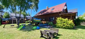 a yard with a playground and a house at Domki Malibu in Tupadła