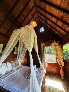 a bed with mosquito netting in a room with windows at Zen Tree House in Silebeng
