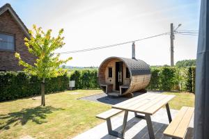 a wooden pod in a yard with a bench and a tree at 't Boshuisje in Poperinge