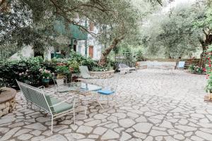 a patio with chairs and tables and trees at Afroditi Pansion in Agios Nikitas