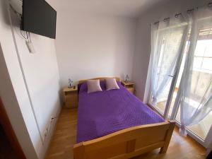 a bedroom with a bed with purple sheets and a window at Guest House Lav in Primošten