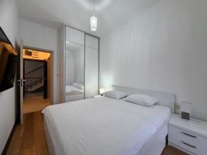 a white bedroom with a large bed and a mirror at Przno in Pržno
