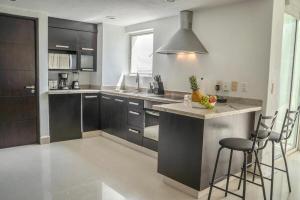 a kitchen with black cabinets and a island with bar stools at Nitta 301 Escápate a Nuevo Vallarta in Nuevo Nayarit