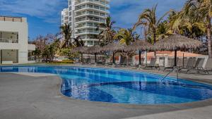 a swimming pool with umbrellas and chairs and a building at Nitta 301 Escápate a Nuevo Vallarta in Nuevo Nayarit
