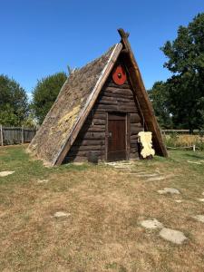 a small log cabin with a thatched roof at les portes de l'histoire in Pleine-Fougères