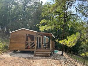 a small wooden cabin in the woods with trees at La Colline aux Chalets, Jaccuzi, Sauna in Saint-Chamarand