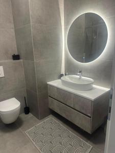 a bathroom with a sink and a toilet and a mirror at Soliq Stay App in Tuzla