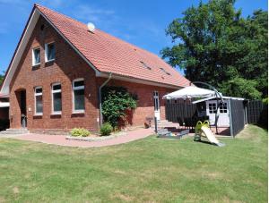 a brick house with a playground in the yard at Ferienwohnung Alte Schule in Lonnerbecke